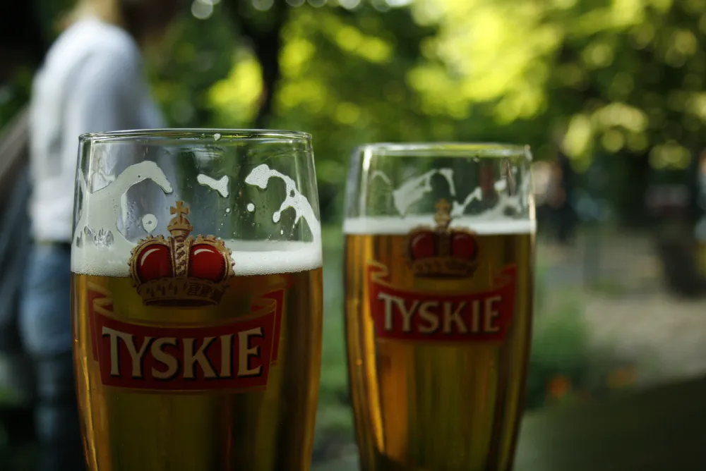 Two glasses of Tyskie beer, priced affordably in Krakow, sit on a table with a blurred background.
